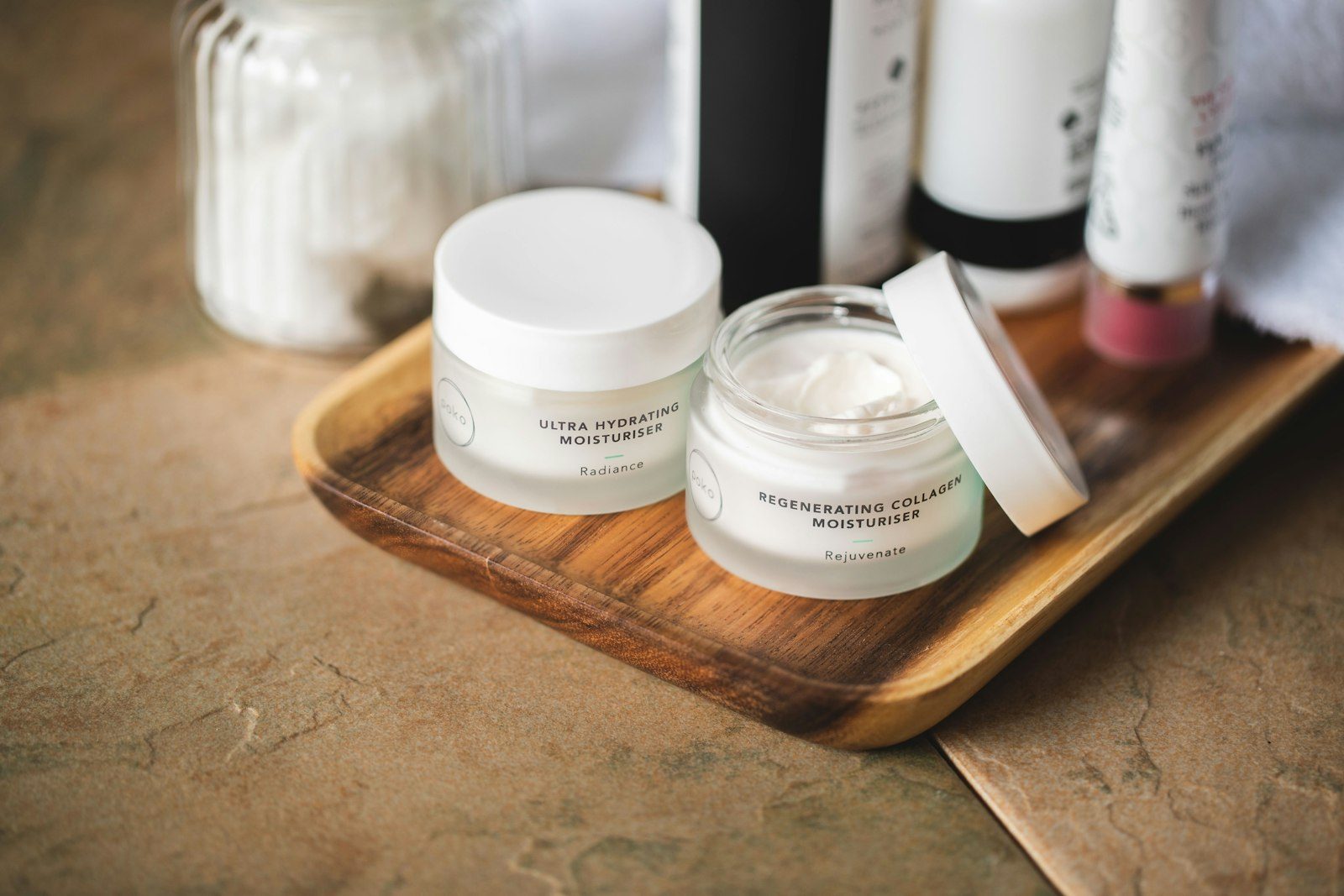 Cream jars with white lids arranged on a wooden tray
