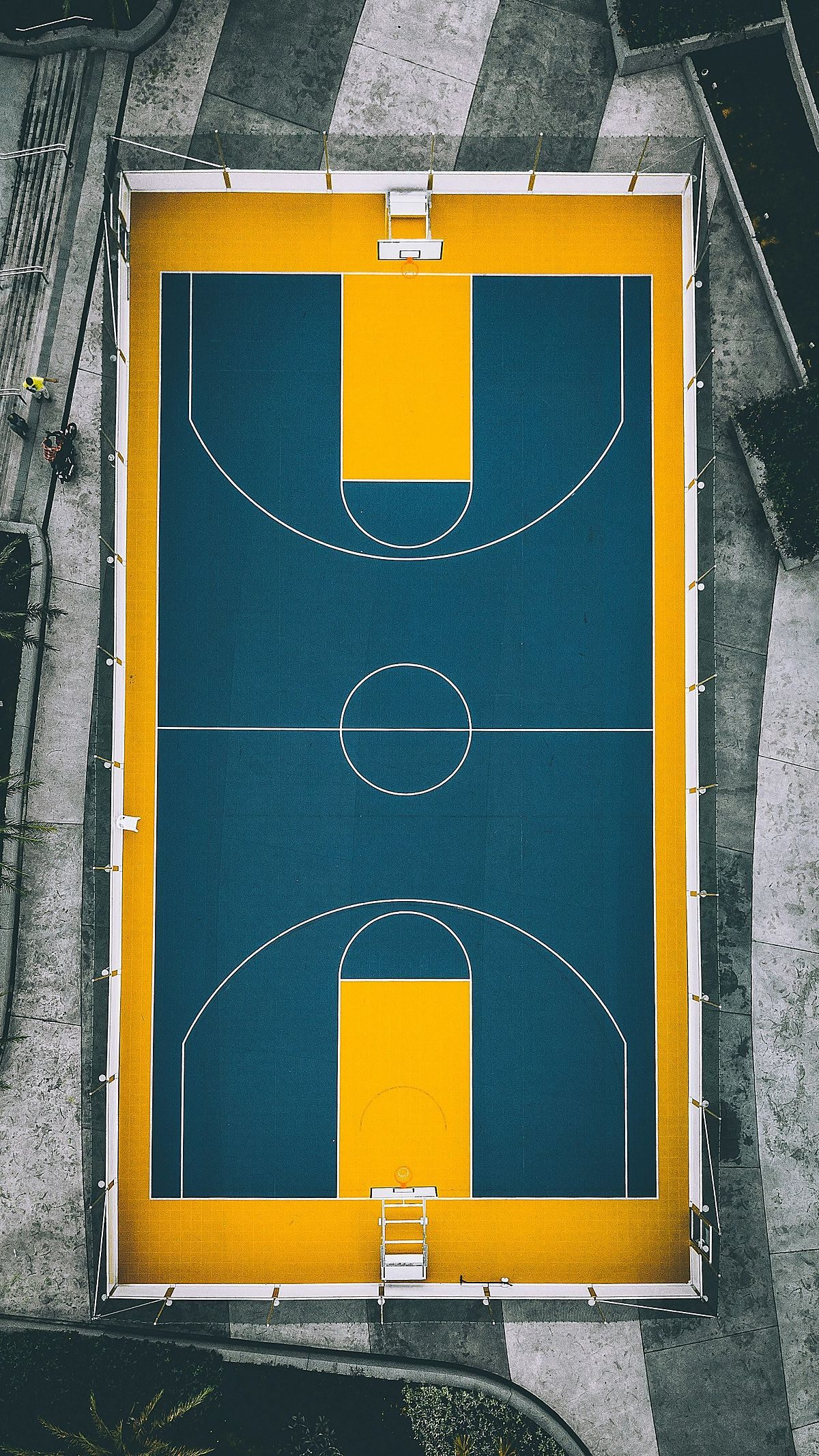 A basketball court painted teal on golden yellow, seen from above