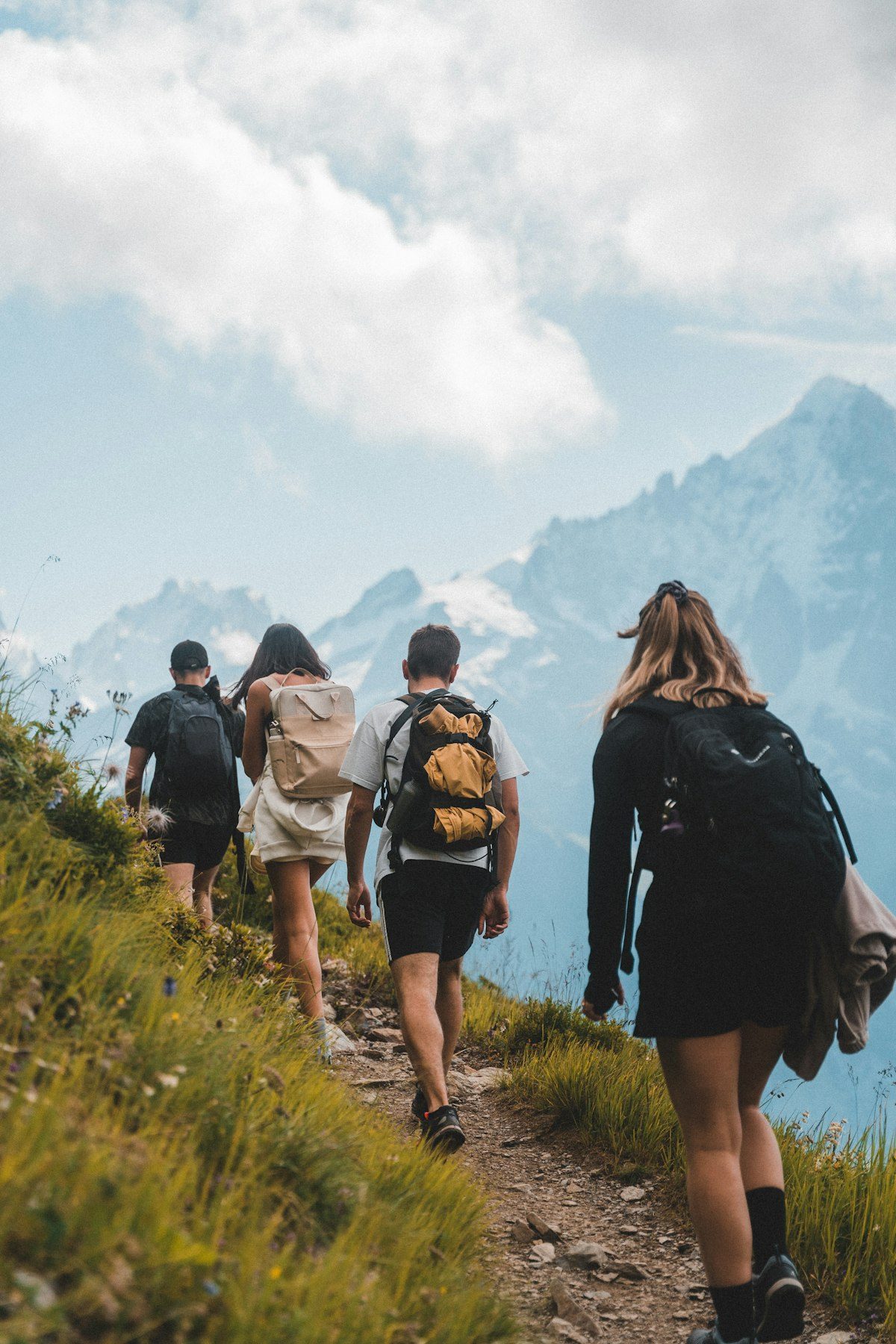 Walkers on a flower-lined path beneath the Mont Blanc massif