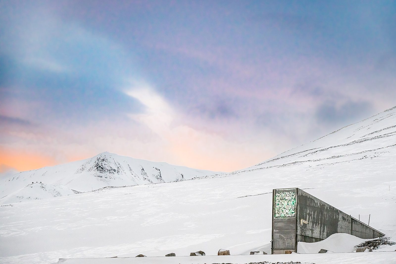 The angular concrete entrance of the Svalbard Global Seed Vault glowing against Arctic snow