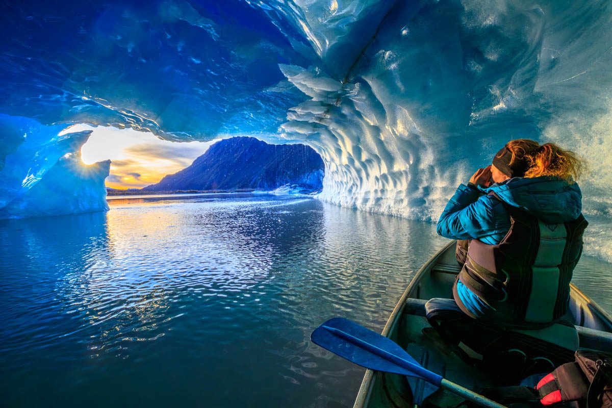 A canoe drifting through a blue ice cave near Valdez at sunset, photographed by Zachery Sheldon